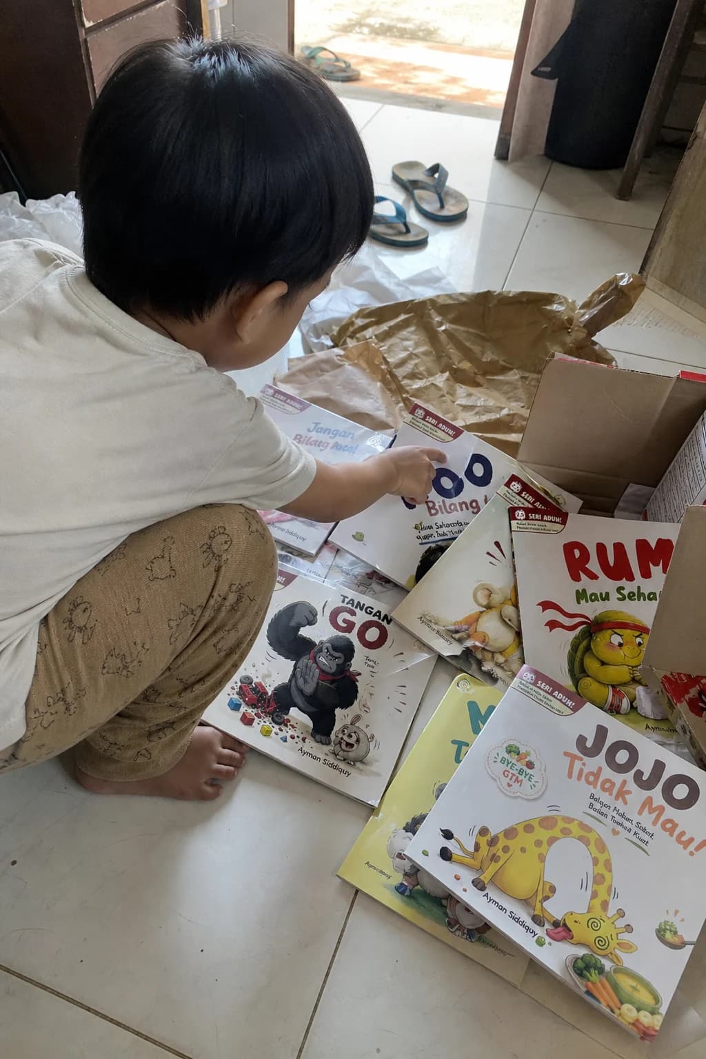 Anak membuka paket dan memilih beberapa judul Seri Aduh